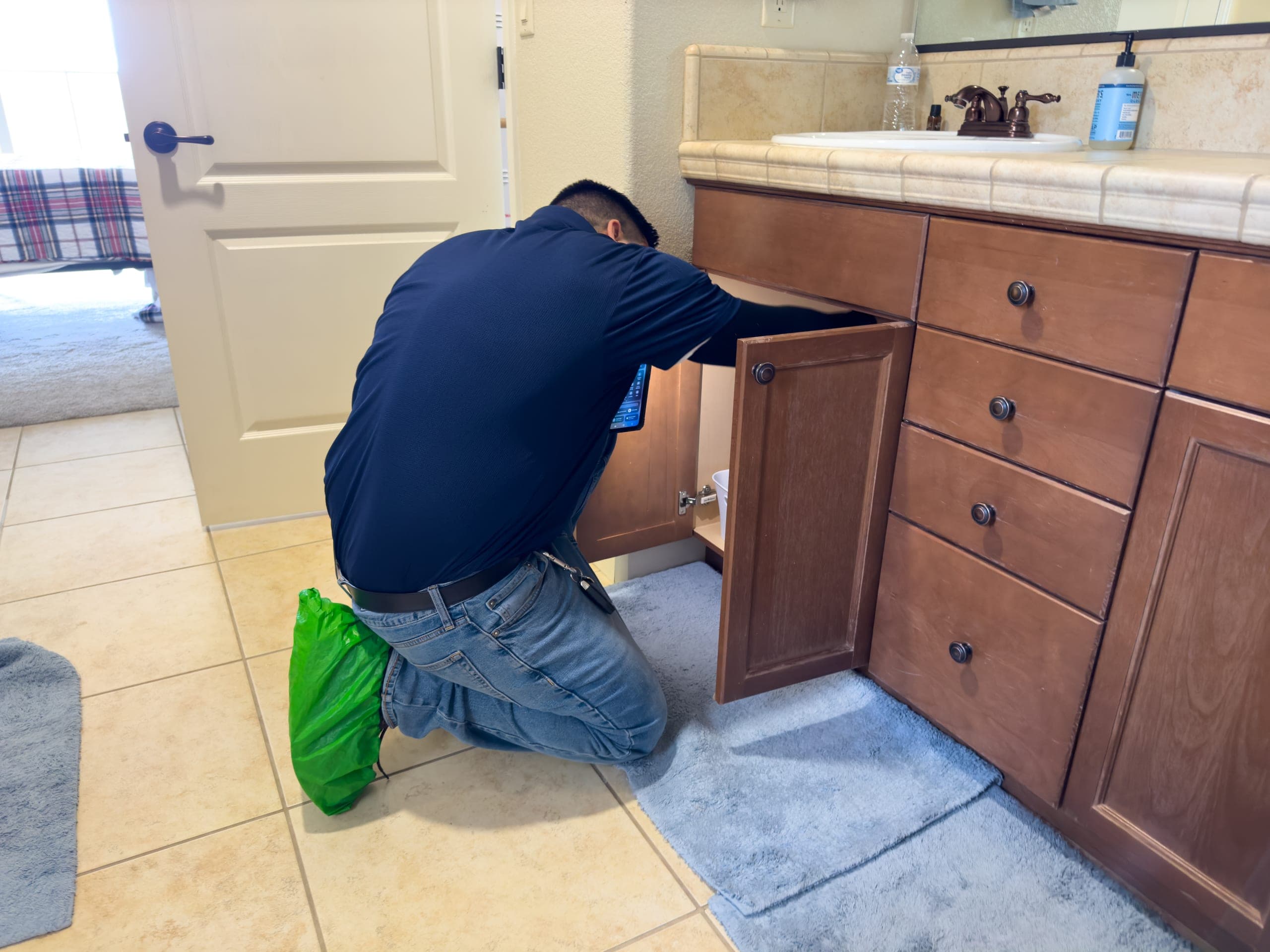 ClearFlow technician inspecting pipes under a kitchen sink